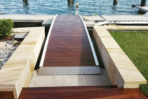 Timber walkway leading from a stone-lined garden to a waterfront jetty - Finish