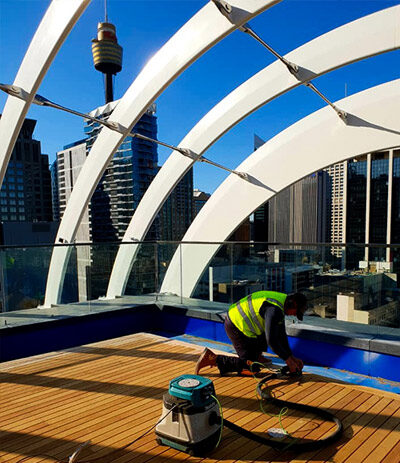Contractor sanding timber rooftop deck.