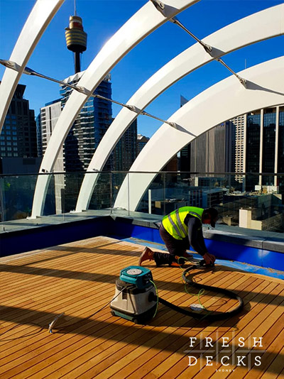 Contractor sanding timber rooftop deck.